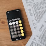 Black Calculator and Tax Forms On Wooden Surface
