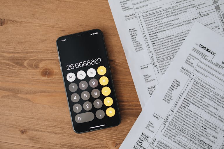 Black Calculator and Tax Forms On Wooden Surface