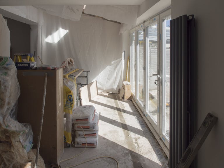 A construction area featuring renovation work in progress with large windows bringing in natural light.